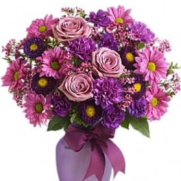 Purple and pink bouquet in a lavender vase with a ribbon