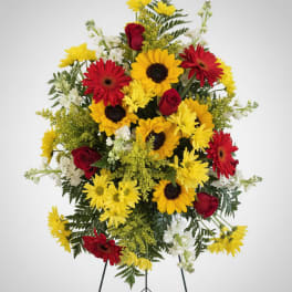 Standing floral spray with red roses, yellow daisies, and white accents