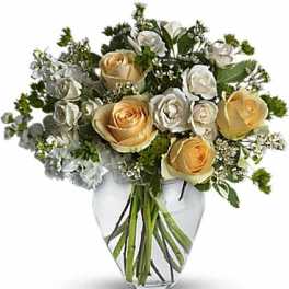 Bouquet of cream and pale yellow roses in a clear glass vase