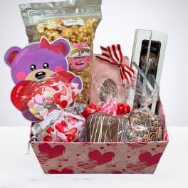 Gift basket with candy, popcorn, and chocolates in a heart-patterned box