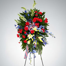Standing floral spray with red, white, and blue flowers on a tripod easel