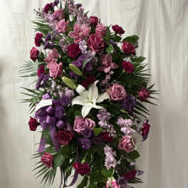 Standing floral spray with pink and purple flowers and a white lily