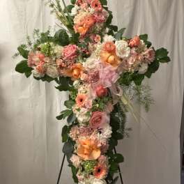 Cross-shaped floral spray with pink, peach, and white flowers on a stand