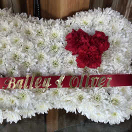 White chrysanthemum arrangement with red carnations and a name ribbon