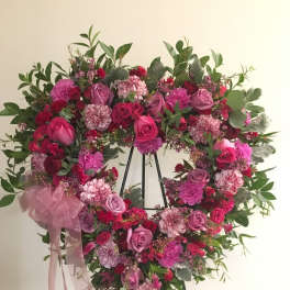 Heart-shaped floral wreath with pink and red roses on a stand