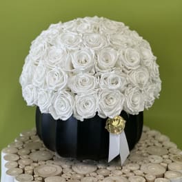 White rose arrangement in a black round box with a ribbon tag