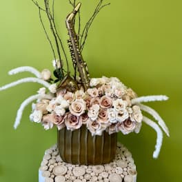 Arrangement of pale roses with a gold saxophone decoration in a brown vase
