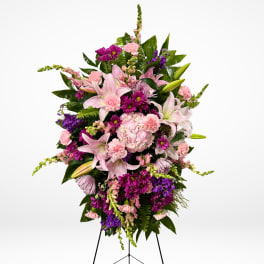 Standing floral spray with pink lilies and purple blooms on an easel
