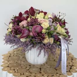 Bouquet of pink, cream, and purple flowers in a white vase