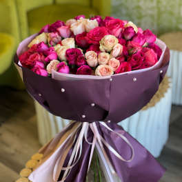 Bouquet of pink and cream roses wrapped in purple paper