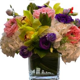 Mixed bouquet of pink, purple, white, and yellow flowers in a glass vase