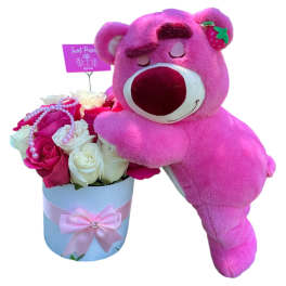Pink teddy bear leaning on a box of roses
