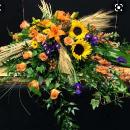 Orange roses and sunflowers arranged with purple flowers and wheat accents