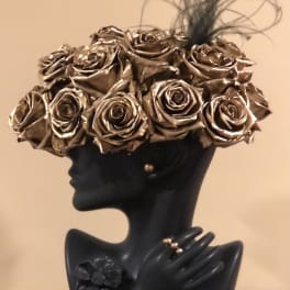 Black bust sculpture topped with metallic gold roses and feather accents