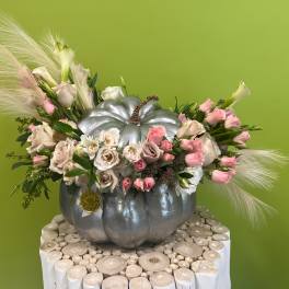 Pink and white flowers arranged in a silver pumpkin container
