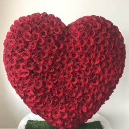 Heart-shaped arrangement of red roses on a white stand