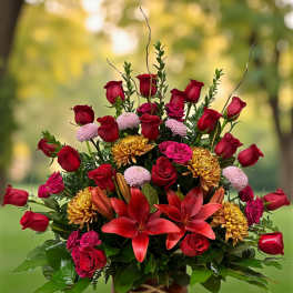 Red roses and lilies arranged in a patterned vase