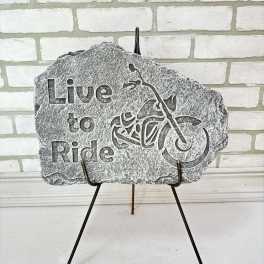 Stone memorial plaque reading "Live to Ride" on a metal stand