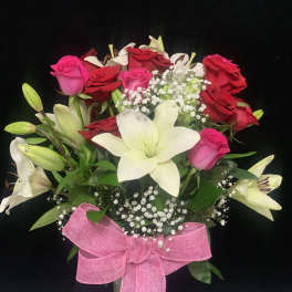 Bouquet of red and pink roses with white lilies in a glass vase