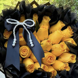 Bouquet of yellow roses wrapped in black paper with a black ribbon and pearl bow