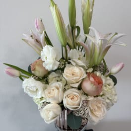 Cream roses and white lilies arranged in a glass vase