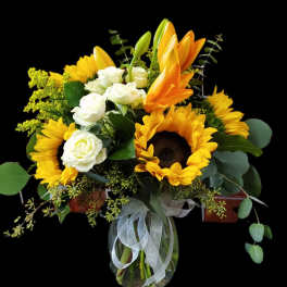 Bouquet of sunflowers, white roses, and orange lilies in a glass vase