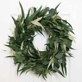 Green foliage wreath with eucalyptus and long leaves on a white door