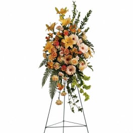 Tall floral standing spray with yellow lilies and peach roses on a metal easel