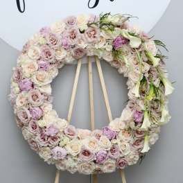 Large pastel floral wreath on a wooden easel with white calla lilies