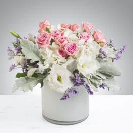 Pink roses and white blooms arranged in a white vase