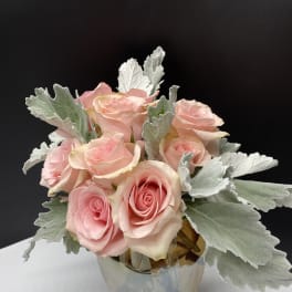 Pink roses arranged in a clear glass vase with silver foliage