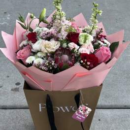 Mixed bouquet of pink, red, and white flowers in pink wrap
