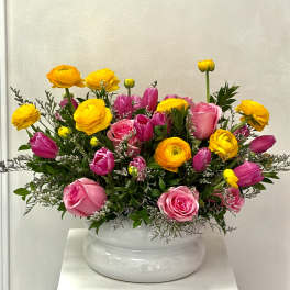 Pink and yellow mixed flower arrangement in a white vase