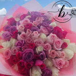 Bouquet of pink, purple, and white roses wrapped in pink paper
