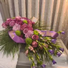 Purple and pink floral casket spray with ribbon