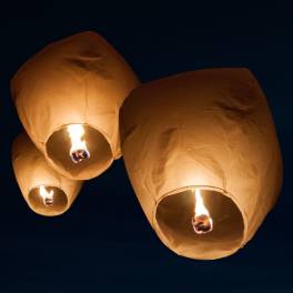 Three glowing sky lanterns floating at night