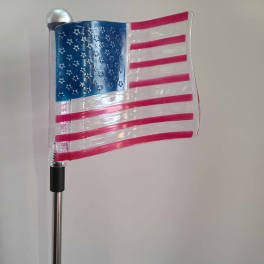 Decorative American flag on a pole against a plain wall