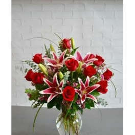 Red roses and pink lilies arranged in a clear glass vase