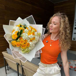 Woman holding a bouquet of yellow roses and white hydrangeas