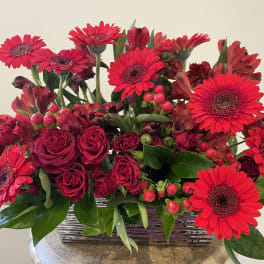 Red gerbera daisies and roses in a low rectangular vase
