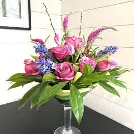 Pink roses and tulips arranged in a clear stemmed vase