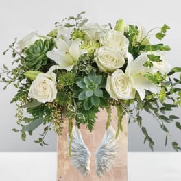 White roses and lilies in a pink vase with angel wings
