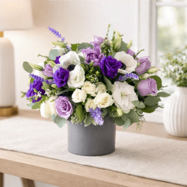 Purple and white floral arrangement in a gray vase