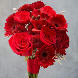 Red rose and gerbera daisy bouquet in a red wrap on a stand