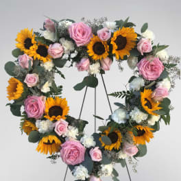 Heart-shaped floral wreath with pink roses, sunflowers, and white carnations