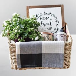 Gift basket with white flowers, a home sign, candle, and soap