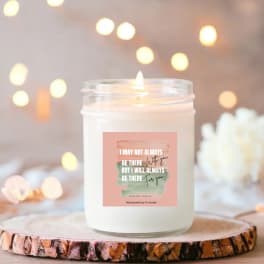 White scented candle in a glass jar with a printed label