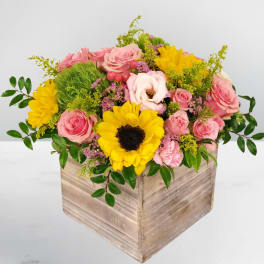 Pink and yellow flower arrangement in a wooden box
