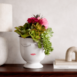 Succulent arrangement in a white face vase with pink flowers