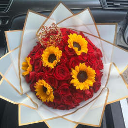 Bouquet of red roses and yellow sunflowers wrapped in white paper
